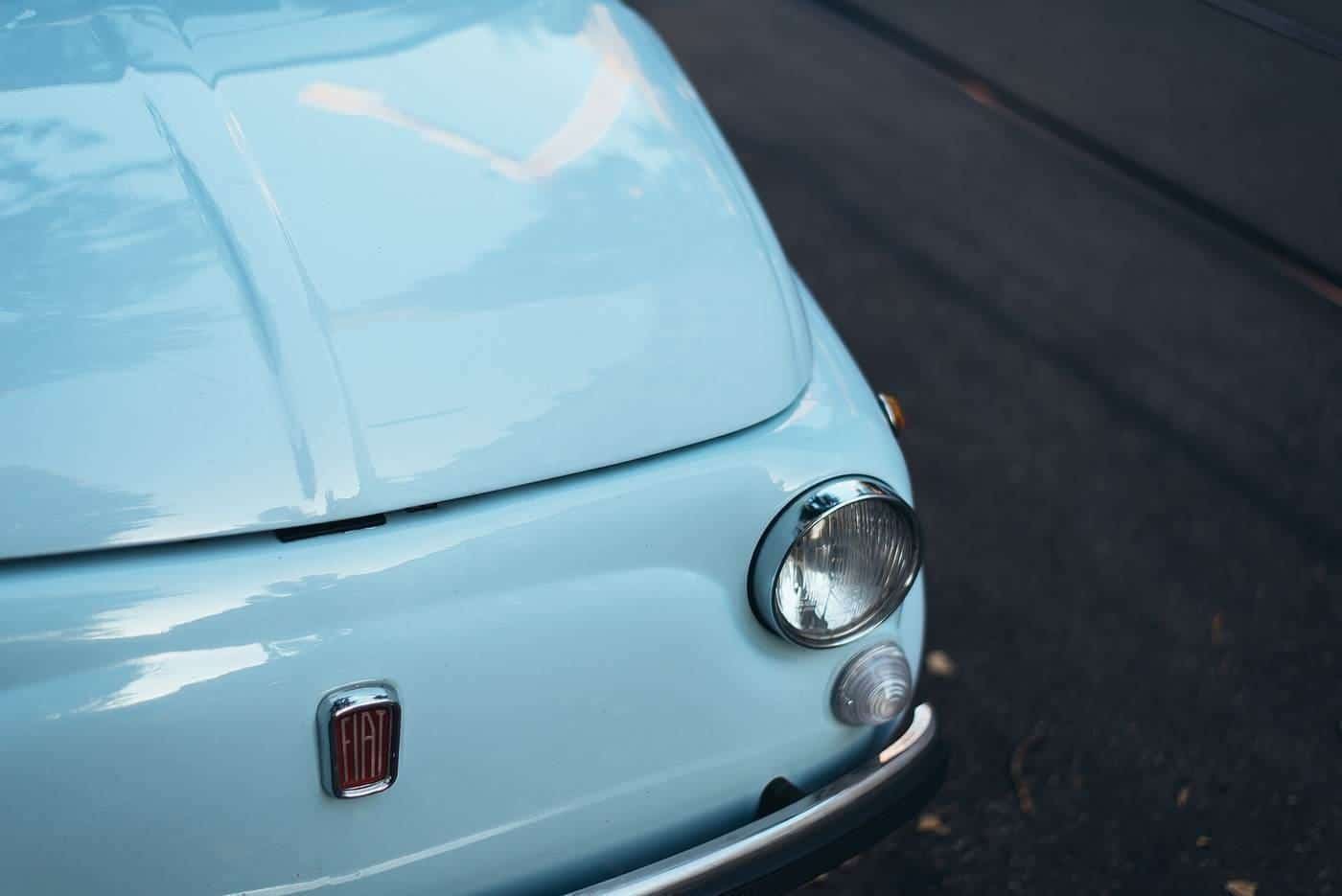 A vintage car headlight on a pale blue car