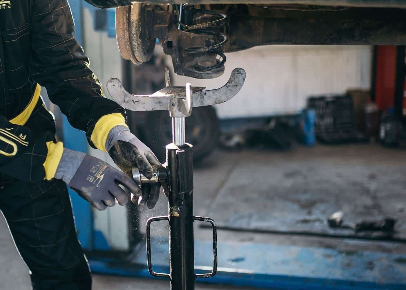 A mechanic working on the suspension of a car raised on a hoist