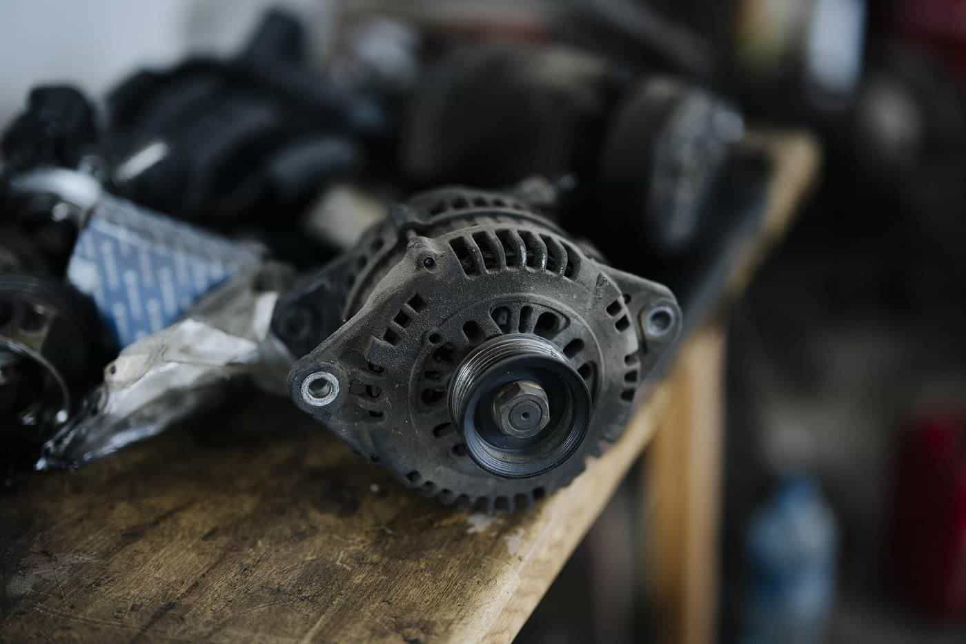 A used car alternator on a workbench among other auto parts