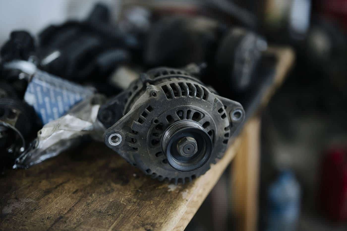 A used car alternator on a workbench among other auto parts