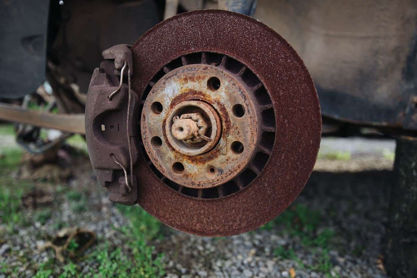 A rusty brake disc and caliper on a car with the wheel removed