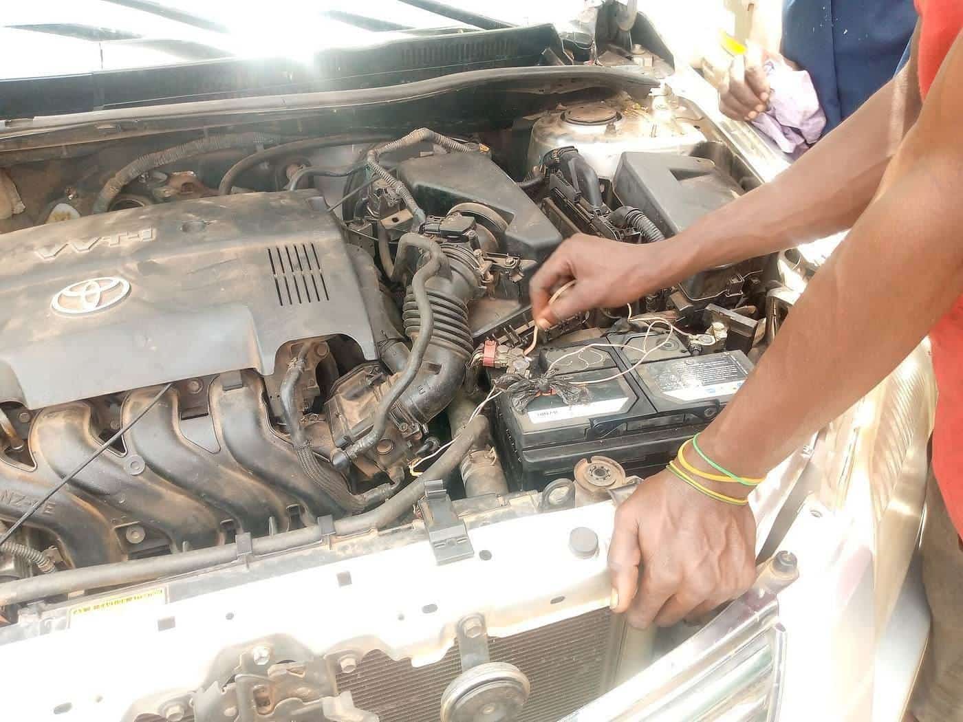 A mechanic checking a car battery in the engine bay